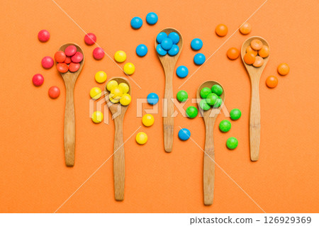 delicious colorful sweet candies on spoon on colored background . Confectionery decor top view with copy space 126929369