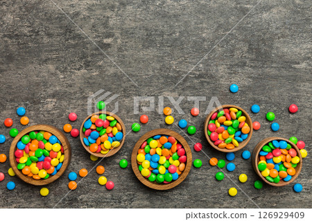different colored round candy in bowl and jars. Top view of large variety sweets and candies with copy space different colored round candy in bowl and jars. Top view of large variety sweets and candies with copy space 126929409