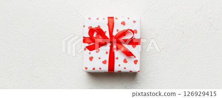 Valentine day composition: red gift box with bow and heart. Christmas present. View from above. Space for text. Holday greeting card Valentine day composition: red gift box with bow and heart. Christmas present. View from above. Space for text. Holday greeting card 126929415