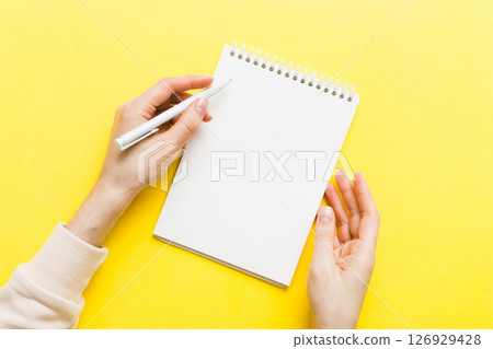 Woman hand with pencil writing on notebook. Woman working on office table. Female hand holding pencil and sketchbook. Mock-up Concept 126929428