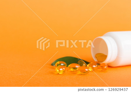 Soft gels pills with Omega-3 oil spilling out of pill bottle close-up. Gel capsules bottle white surface. Omega 3, multivitamins, Calcium, antibiotics. Health. Immunity 126929437