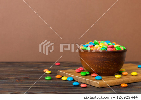 Multicolored candies in a bowl on a colored background. birthday and holiday concept. Top view with copy space 126929444