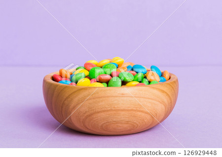 Multicolored candies in a bowl on a colored background. birthday and holiday concept. Top view with copy space 126929448