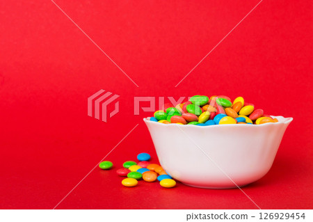 Multicolored candies in a bowl on a colored background. birthday and holiday concept. Top view with copy space 126929454