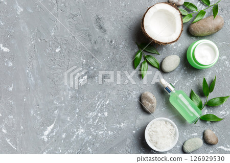 Coconut with jars of coconut oil and cosmetic cream on colored background. Top view. Free space for your text. Natural spa coconut cosmetics and organic treatment concept Coconut Spa composition 126929530