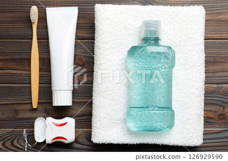 Mouthwash and other oral hygiene products on colored table top view with copy space. Flat lay. Dental hygiene. Oral care products and space for text on light background. concept Mouthwash and other oral hygiene products on colored table top view with copy space. Flat lay. Dental hygiene. Oral care products and space for text on light background. concept 126929590