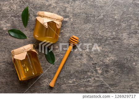 Honey jar with wooden honey dipper on white background top view with copy space. Delicious honey bottle Honey jar with wooden honey dipper on white background top view with copy space. Delicious honey bottle 126929717