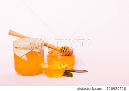 Honey in jar with leaves and honey dipper on colored background top view with copy text 126929718