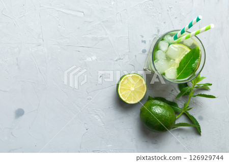 Caipirinha, Mojito cocktail, vodka or soda drink with lime, mint and straw on table background. Refreshing beverage with mint and lime in glass top view flat lay 126929744