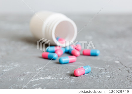 plastic medicine bottle with capsules of pills on colored background. Online pharmacy. Painkiller medicine and antibiotic drug resistance concept. Pharmaceutical industry plastic medicine bottle with capsules of pills on colored background. Online pharmacy. Painkiller medicine and antibiotic drug resistance concept. Pharmaceutical industry 126929749