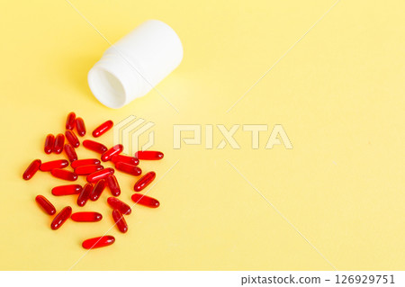 Red pills spilled around a pill bottle. Medicines and prescription pills flat lay background. Red medical capsules 126929751