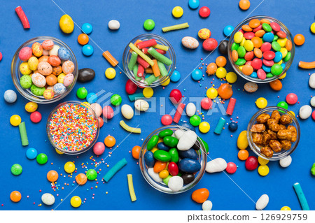 different colored round candy in bowl and jars. Top view of large variety sweets and candies with copy space different colored round candy in bowl and jars. Top view of large variety sweets and candies with copy space 126929759