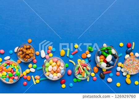 different colored round candy in bowl and jars. Top view of large variety sweets and candies with copy space different colored round candy in bowl and jars. Top view of large variety sweets and candies with copy space 126929760