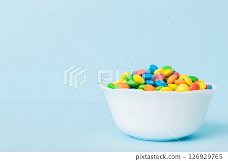 Multicolored candies in a bowl on a colored background. birthday and holiday concept. Top view with copy space 126929765