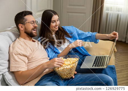 Family spending weekend at home enjoying popcorn and watching online comedy movie Family spending weekend at home enjoying popcorn and watching online comedy movie 126929775