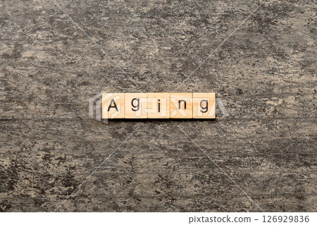 Aging word written on wood block. Aging text on cement table for your desing, concept Aging word written on wood block. Aging text on cement table for your desing, concept 126929836