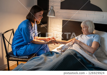 Doctor checking pulse of an elderly patient and looking focused Doctor checking pulse of an elderly patient and looking focused 126929924