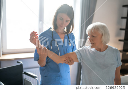 Female doctor in rehabilitation center examining elderly patient 126929925