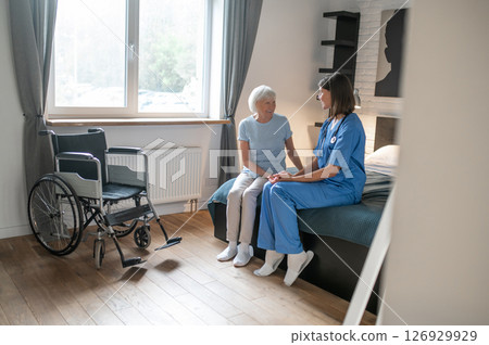 Female doctor in rehabilitation center examining elderly patient 126929929