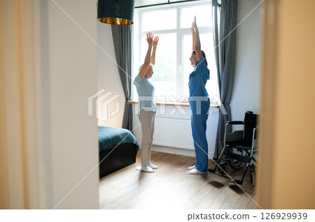 Elderly lady exercising with an instructor and looking involved 126929939