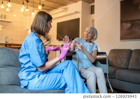 Nurse in uniform preparing medicine for an injection, elderly patient looking scared Nurse in uniform preparing medicine for an injection, elderly patient looking scared 126929943