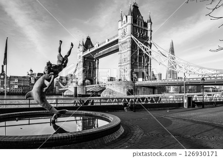 Girl with a Dolphin - girl playfully leaps with a dolphin at a statue located by Tower Bridge, creating a charming scene in the heart of London. The iconic structure stands proudly in the background. Girl with a Dolphin - girl playfully leaps with a dolphin at a statue located by Tower Bridge, creating a charming scene in the heart of London. The iconic structure stands proudly in the background. 126930171