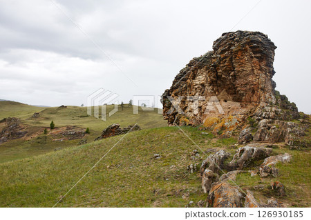 Unique rock formations rise above the grassy terrain. 126930185