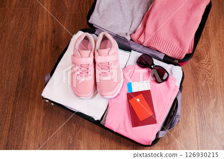 An open suitcase with clothes, sneakers, sunglasses. Passport, card, tickets for the trip. 126930215