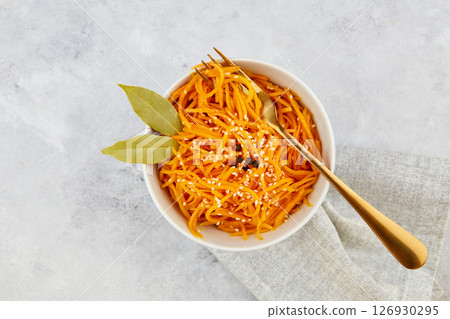 Spicy pickled carrots in a bowl on a grey background, spicy Korean appetizer. Vegan healthy food. Close-up Spicy pickled carrots in a bowl on a grey background, spicy Korean appetizer. Vegan healthy food. Close-up 126930295