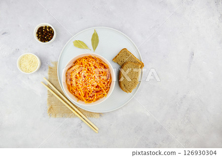 Spicy pickled carrots in a bowl on a grey background, spicy Korean appetizer. 126930304