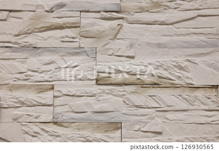 Textured stone wall featuring a natural, rustic design with warm tones and intricate patterns in a contemporary setting 126930565