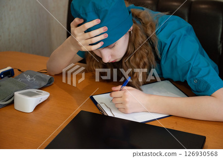 Medical student studies diligently while feeling overwhelmed at a desk in a quiet study space 126930568