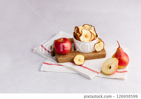 Homemade dried sliced apple and pear in a bowl on a light gray background. 126930599