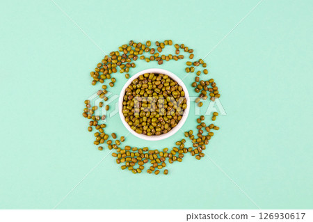 Mung beans in ceramic bowl on a green background. Mung beans in ceramic bowl on a green background. 126930617