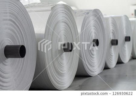 A warehouse with large white rolls of polypropylene. A warehouse with large white rolls of polypropylene. 126930622
