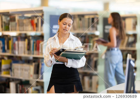 woman stands with textbooks in front of students 126930689
