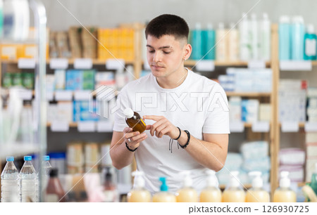 man chooses cough syrup in a pharmacy man chooses cough syrup in a pharmacy 126930725