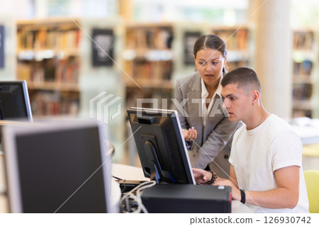 Female student helping guy student work on computer Female student helping guy student work on computer 126930742