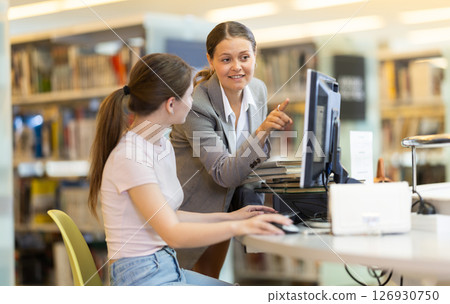 Female student helping female student work on computer Female student helping female student work on computer 126930750