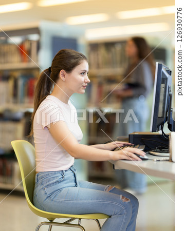 Female student working on computer in library Female student working on computer in library 126930776