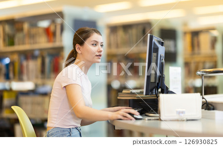 Young female student working on computer in library Young female student working on computer in library 126930825