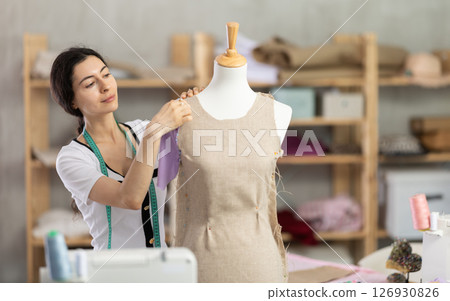 Seamstress shaping dress on mannequin in tailoring studio 126930826