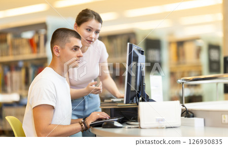 guy is working at a computer against the background of a young woman 126930835