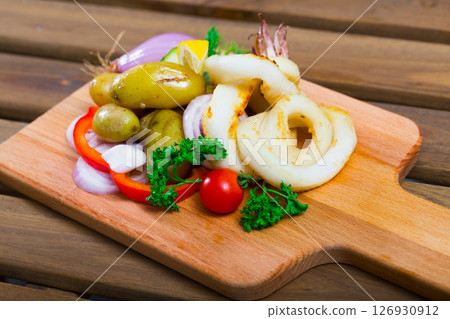 Squid rings with potatoes and fresh vegetables and herbs served at plate Squid rings with potatoes and fresh vegetables and herbs served at plate 126930912