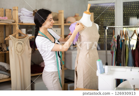 Seamstress shaping dress on mannequin in tailoring studio 126930913