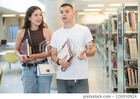 Students walk near the shelves and communicate 126930924