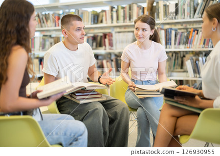 Group of students reading and discussing books in library Group of students reading and discussing books in library 126930955
