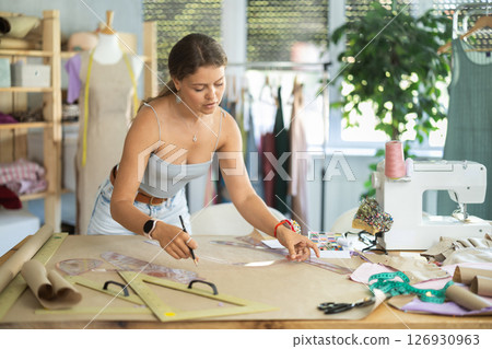 Young fashion designer drawing patterns on paper 126930963