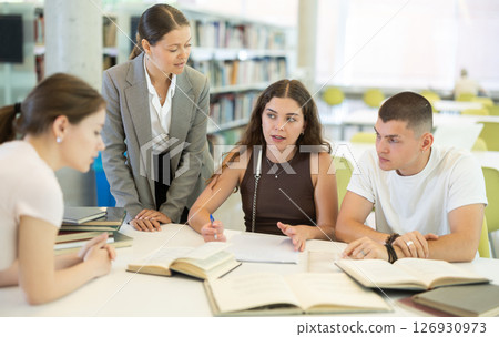 Group of students reading books and taking notes in library Group of students reading books and taking notes in library 126930973