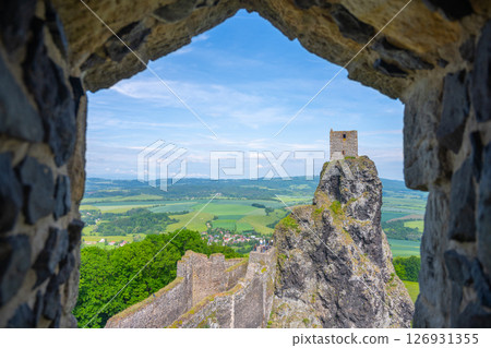 Trosky Castle ruins rise majestically over lush green landscapes of Bohemian Paradise, offering panoramic views of the surrounding countryside under a clear blue sky. 126931355